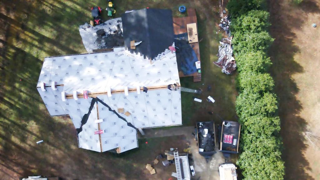 A drone view of a large house in Raleigh-Durham with a newly installed roof, showcasing clean shingles and a well-structured roofline.