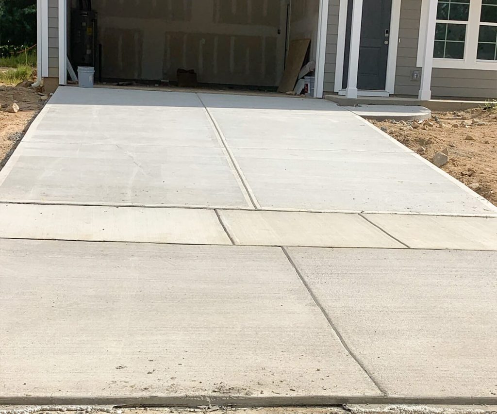 A newly completed driveway with a pristine, smooth surface, showcasing a well-finished and functional addition to the home.