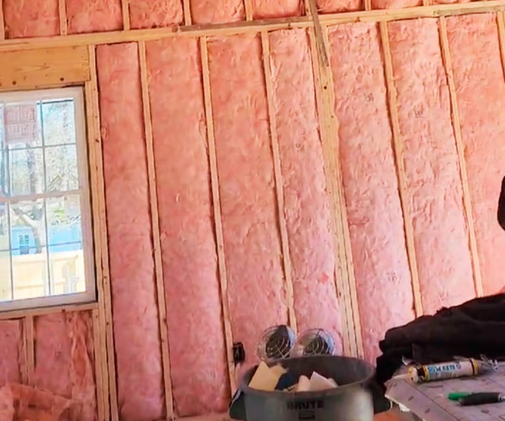 A general contractor supervising the framing and insulation process in a construction project, showing the structured framework and insulation materials in place.