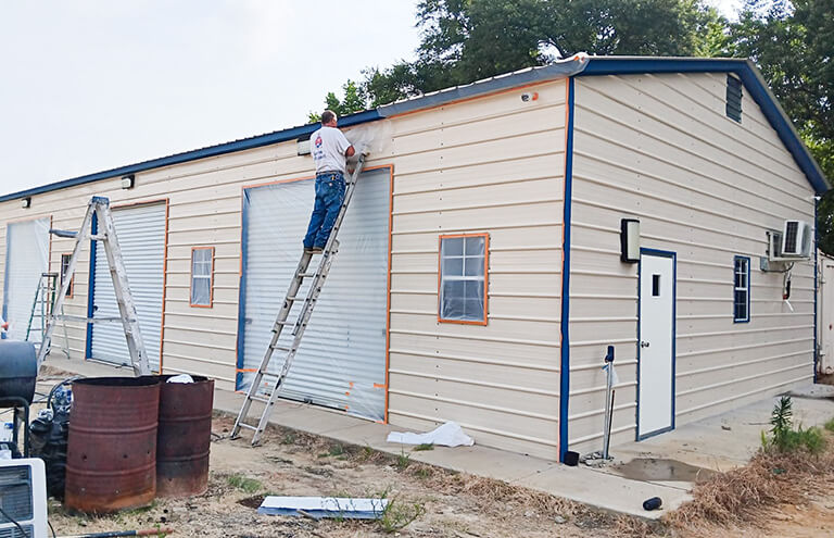 Painters applying a fresh coat of paint to the exterior of a home, showing the preparation and painting process in progress.