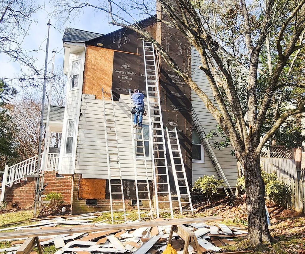 A team of professionals installing new siding on a home, demonstrating skilled workmanship and attention to detail during the installation process.